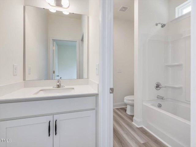 bathroom featuring wood finished floors, toilet, vanity, visible vents, and washtub / shower combination