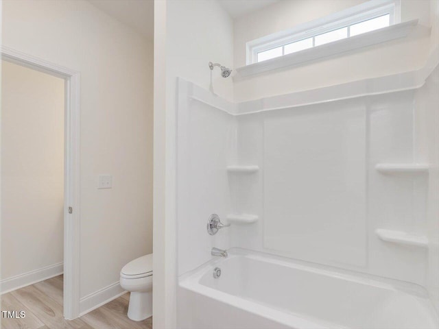 full bath featuring toilet, washtub / shower combination, wood finished floors, and baseboards