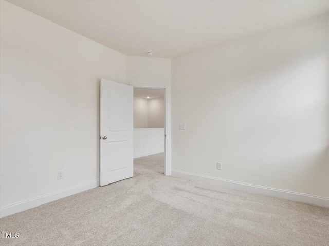 unfurnished room with baseboards and light colored carpet