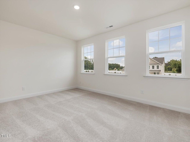 empty room with visible vents, light colored carpet, and baseboards