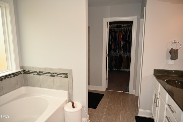 474 Ashpole Trl, Clayton, NC 27520 - bathroom with a garden tub, a spacious closet, vanity, and baseboards