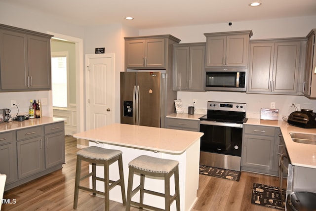 474 Ashpole Trl, Clayton, NC 27520 - kitchen featuring appliances with stainless steel finishes, gray cabinets, a kitchen breakfast bar, light wood finished floors, and recessed lighting