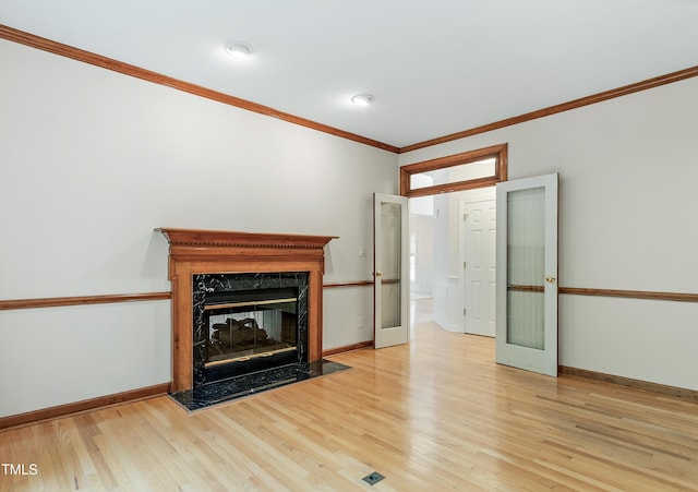 unfurnished living room with crown molding, light wood-style flooring, baseboards, and a premium fireplace