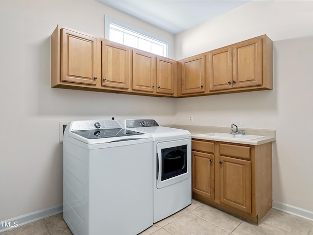 washroom with cabinet space, a sink, baseboards, light tile patterned floors, and washing machine and dryer