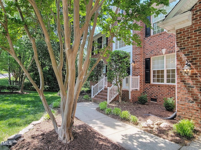 doorway to property featuring a yard and brick siding