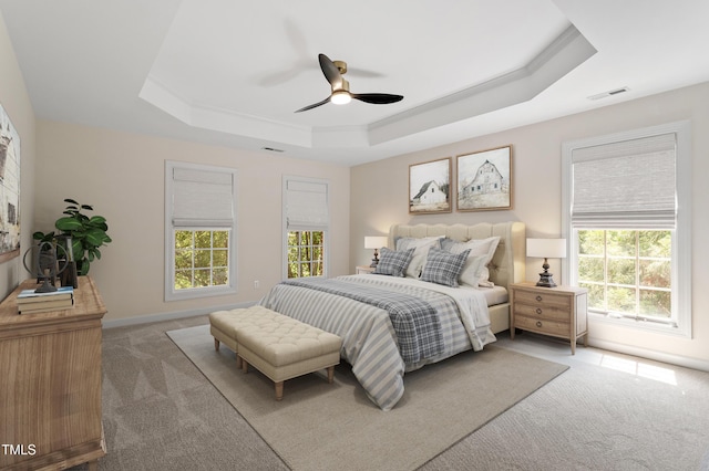 bedroom featuring visible vents, a ceiling fan, a raised ceiling, and light carpet