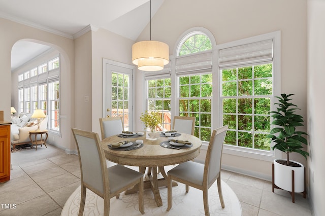 dining area with arched walkways, light tile patterned floors, a healthy amount of sunlight, and ornamental molding