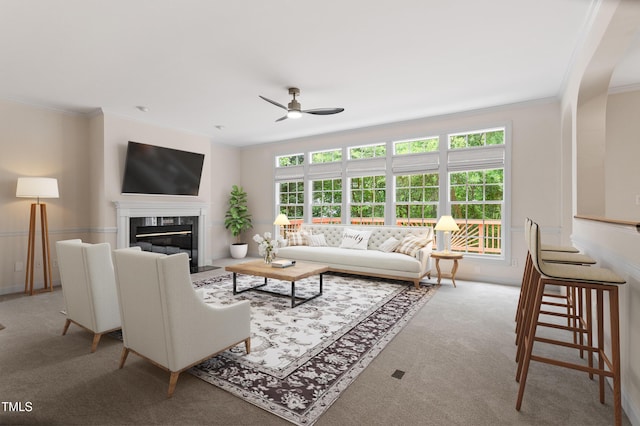 carpeted living area featuring crown molding, a ceiling fan, arched walkways, and a fireplace