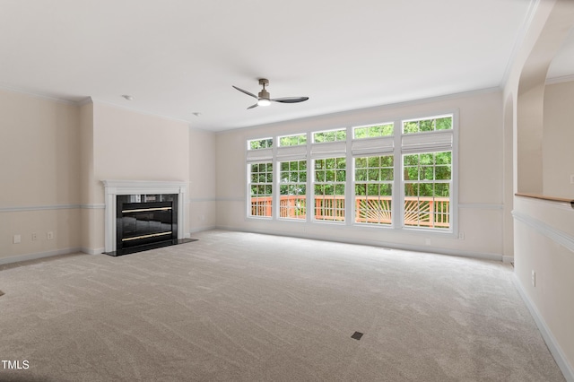 unfurnished living room with carpet flooring, ceiling fan, a premium fireplace, and ornamental molding