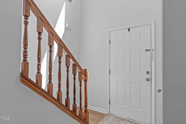 foyer entrance with stairs, baseboards, and wood finished floors