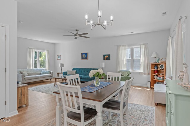dining room with baseboards, ceiling fan with notable chandelier, light wood-style flooring, and visible vents