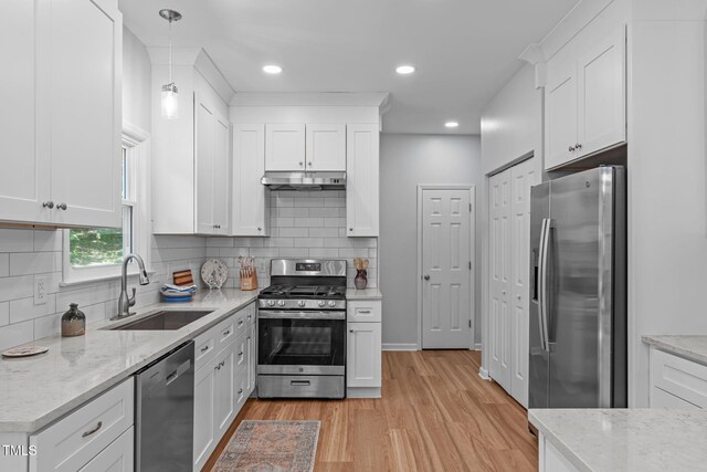 kitchen featuring under cabinet range hood, stainless steel appliances, white cabinetry, and a sink
