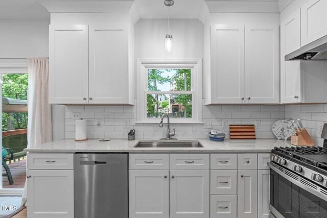 kitchen featuring a healthy amount of sunlight, decorative backsplash, appliances with stainless steel finishes, a sink, and white cabinetry
