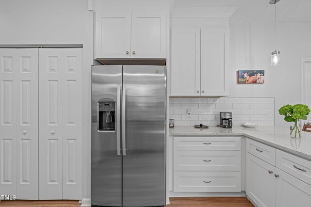 kitchen featuring light stone counters, white cabinetry, decorative light fixtures, decorative backsplash, and stainless steel refrigerator with ice dispenser