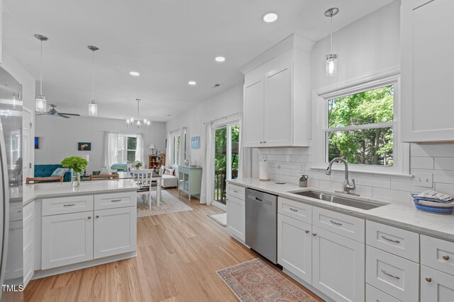 kitchen with a sink, a healthy amount of sunlight, stainless steel dishwasher, and open floor plan
