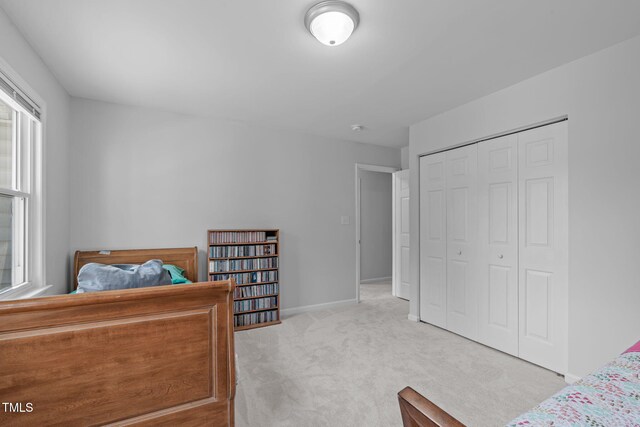 carpeted bedroom featuring a closet and baseboards