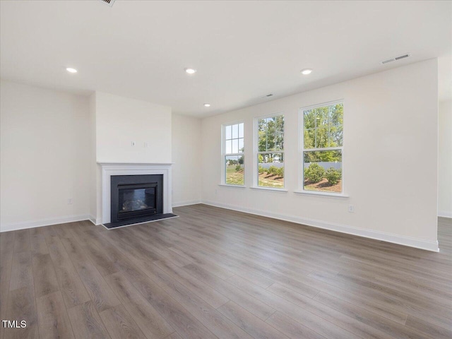 33 Celtic Ln, Lillington, NC 27546 - unfurnished living room featuring visible vents, wood finished floors, a fireplace with flush hearth, and recessed lighting