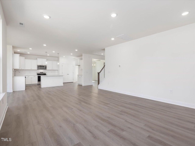 33 Celtic Ln, Lillington, NC 27546 - unfurnished living room featuring baseboards, recessed lighting, light wood-type flooring, and stairway