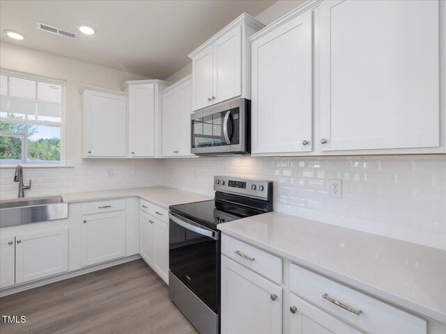 33 Celtic Ln, Lillington, NC 27546 - kitchen with white cabinetry, a sink, appliances with stainless steel finishes, visible vents, and backsplash