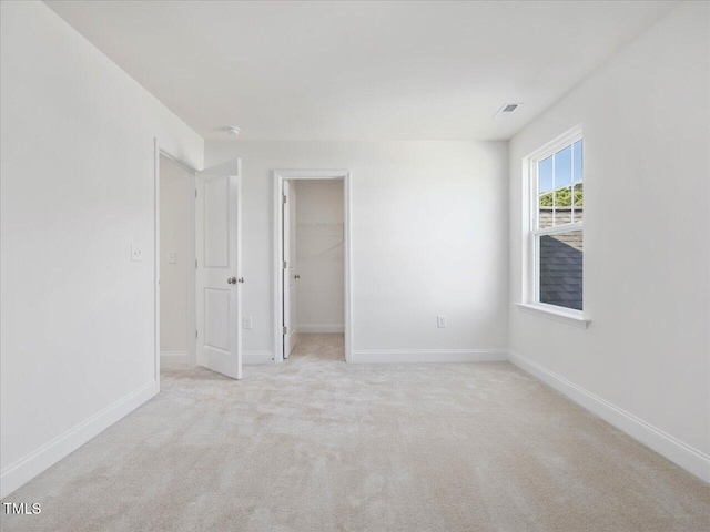 33 Celtic Ln, Lillington, NC 27546 - unfurnished bedroom featuring a walk in closet, visible vents, light colored carpet, and baseboards