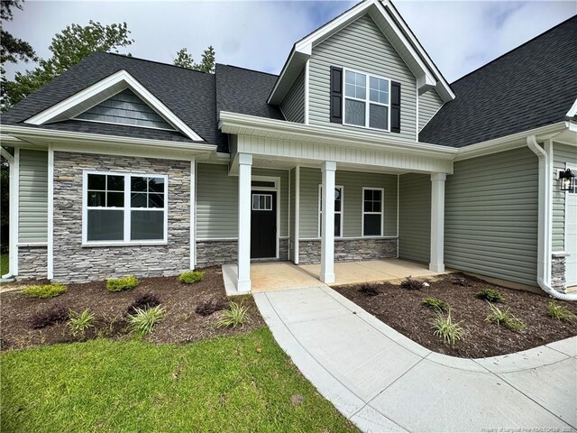 374 Whitestone Dr, Fayetteville, NC 28312 - craftsman-style house featuring covered porch, roof with shingles, and stone siding