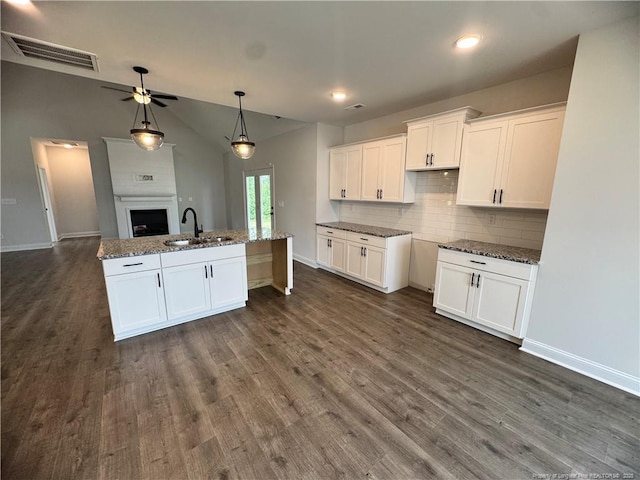 374 Whitestone Dr, Fayetteville, NC 28312 - kitchen with white cabinetry, backsplash, stone counters, dark wood-style flooring, and vaulted ceiling