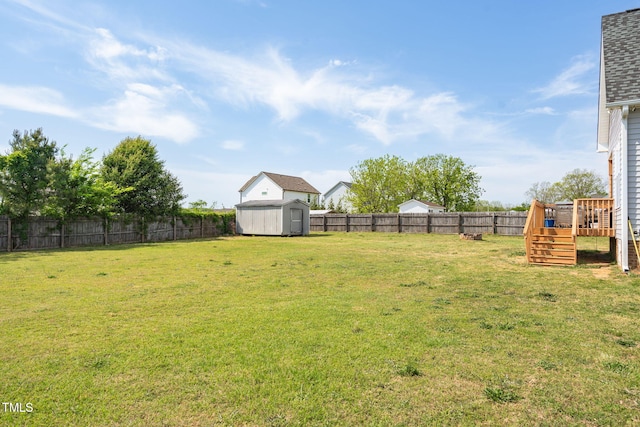view of yard with an outdoor structure, a fenced backyard, a wooden deck, and a storage shed