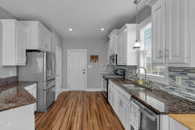 kitchen featuring a sink, decorative backsplash, stainless steel appliances, dark wood-type flooring, and white cabinetry