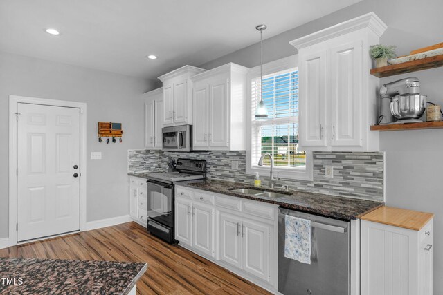 kitchen featuring wood finished floors, stainless steel appliances, open shelves, white cabinets, and a sink