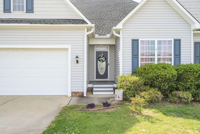 doorway to property featuring concrete driveway, a yard, a shingled roof, and a garage