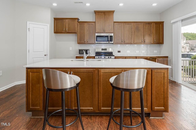 1018 Excite Ave, Morrisville, NC 27560 - kitchen with appliances with stainless steel finishes, dark wood finished floors, brown cabinetry, tasteful backsplash, and light countertops