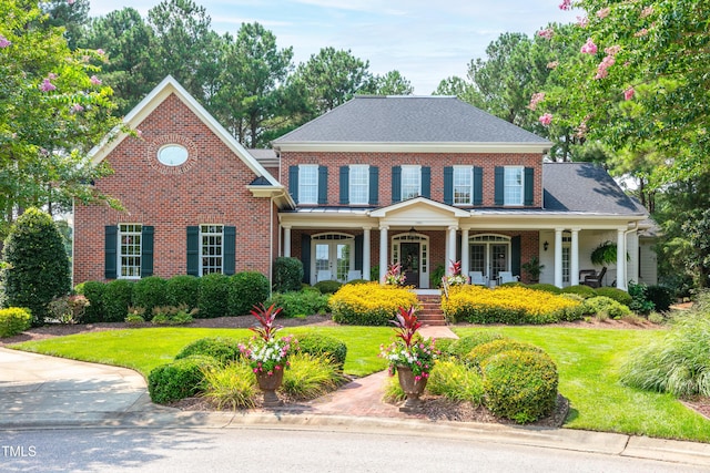 view of front of property featuring a porch, brick siding, and a front lawn