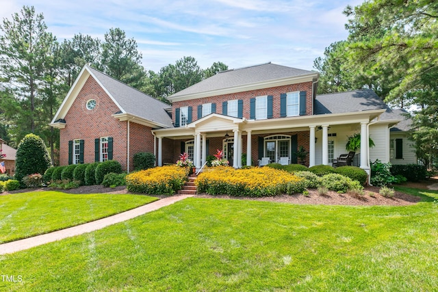view of front facade featuring brick siding, a ceiling fan, a front yard, and a porch