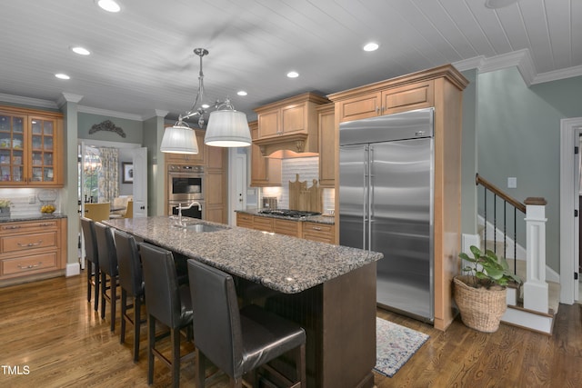 kitchen with appliances with stainless steel finishes, a sink, recessed lighting, a kitchen bar, and ornamental molding