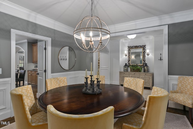 dining area featuring a wainscoted wall, ornamental molding, a decorative wall, and a chandelier