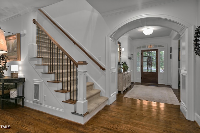 foyer with crown molding, arched walkways, stairs, and wood finished floors