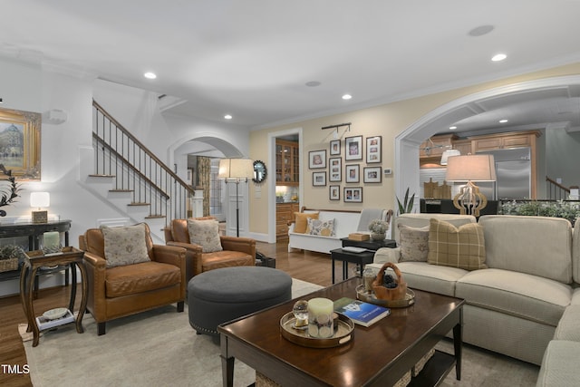living area with arched walkways, recessed lighting, ornamental molding, and stairway