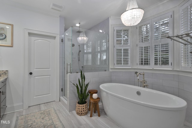 full bathroom with crown molding, a stall shower, vanity, an inviting chandelier, and a soaking tub
