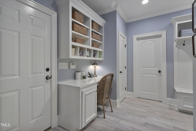 office with built in study area, baseboards, crown molding, and light wood-style flooring