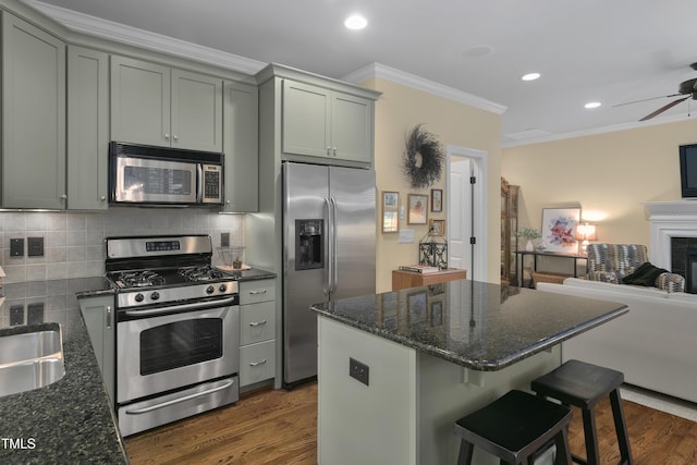 kitchen featuring ornamental molding, stainless steel appliances, open floor plan, a ceiling fan, and dark wood-style floors