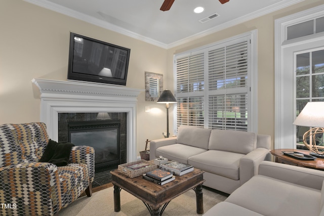 living room featuring crown molding, ceiling fan, visible vents, and a fireplace