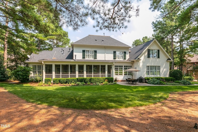 back of house featuring a yard, a shingled roof, a sunroom, and a patio area