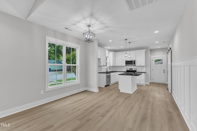 401 N Raiford St, Selma, NC 27576 - kitchen featuring appliances with stainless steel finishes, a barn door, white cabinetry, recessed lighting, and light wood-style floors
