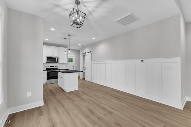 401 N Raiford St, Selma, NC 27576 - kitchen featuring stainless steel appliances, a barn door, light wood-type flooring, white cabinets, and recessed lighting