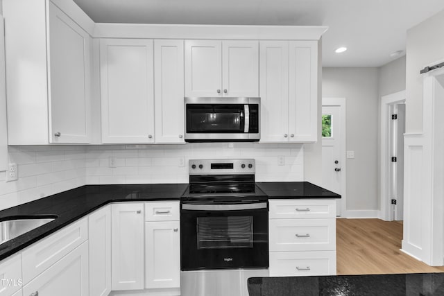 401 N Raiford St, Selma, NC 27576 - kitchen featuring appliances with stainless steel finishes, white cabinets, tasteful backsplash, light wood-style floors, and recessed lighting