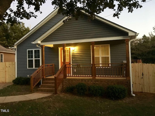 bungalow featuring covered porch and fence