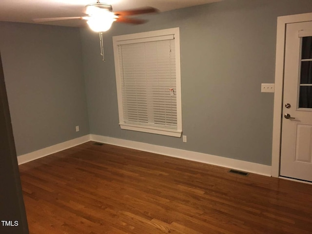 spare room with dark wood finished floors, baseboards, visible vents, and a ceiling fan