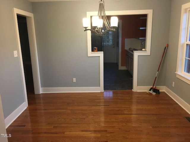 unfurnished dining area with an inviting chandelier, wood finished floors, and baseboards