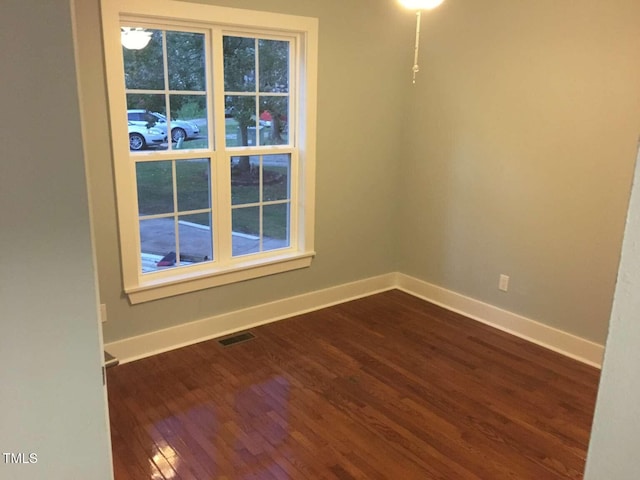 spare room with visible vents, a healthy amount of sunlight, dark wood-style floors, and baseboards