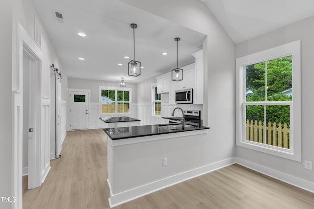405 N Raiford St, Selma, NC 27576 - kitchen with appliances with stainless steel finishes, a sink, white cabinets, a barn door, and light wood-type flooring